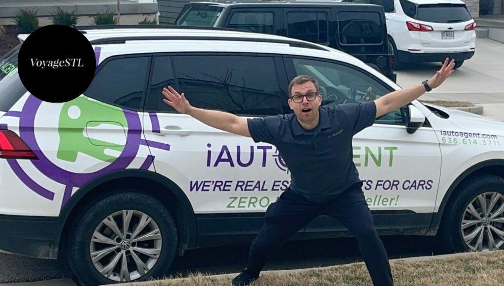 Jay Grosman stands with arms spread apart in excitement with a white iAutoAgent SUV in the background